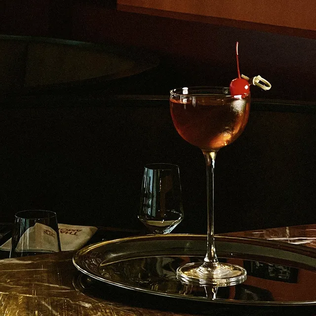 Ein genussvoll angerichteter Cocktail steht auf einem silbernen Tablett. 