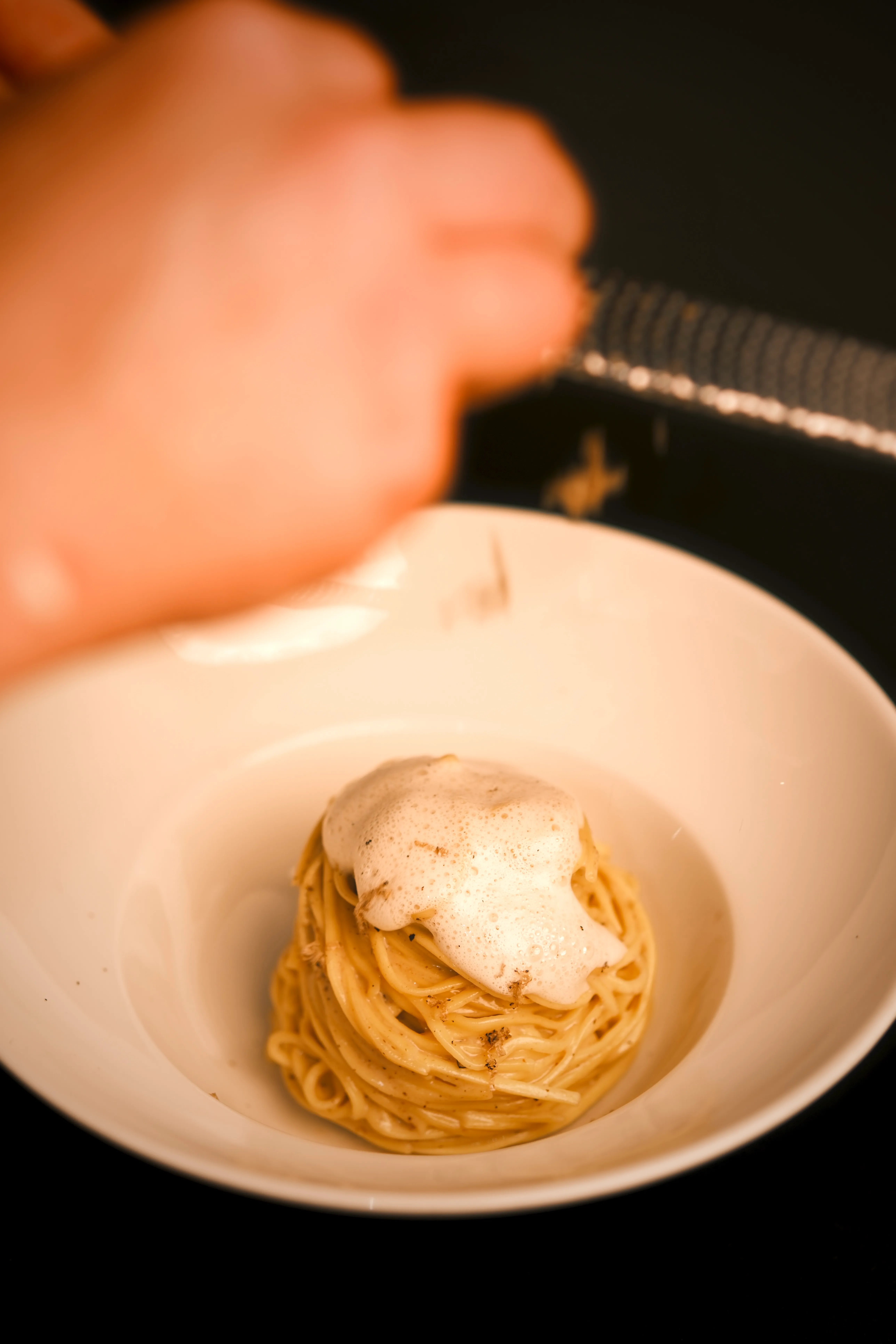 Ein Bild von Trüffel-Spaghetti, auf die Trüffel gehobelt wird.