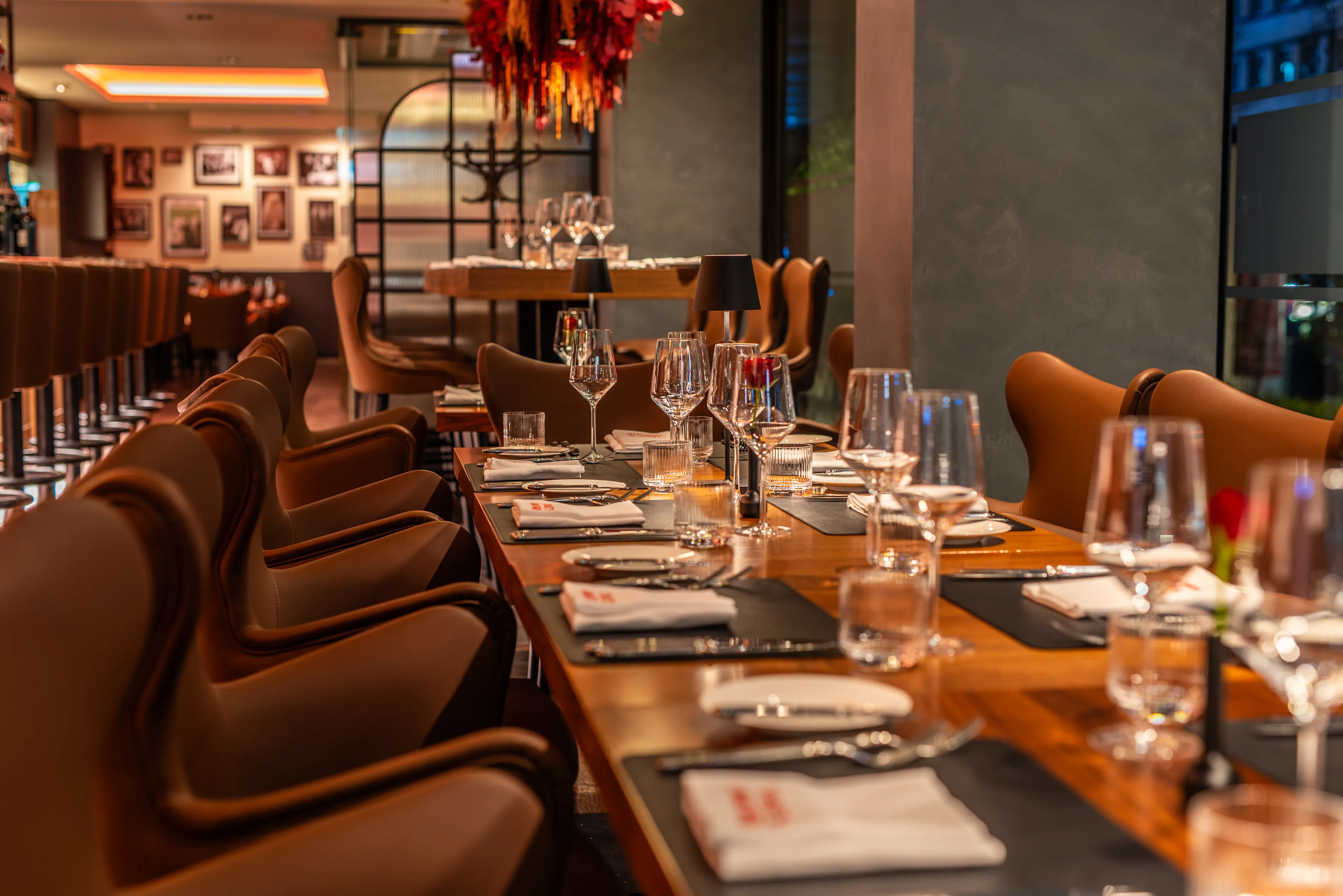 Blick auf den festlich gedeckten Innenraum des Restaurants mit langen Tafeln, Gläsern, Kerzen und stilvoller Beleuchtung.