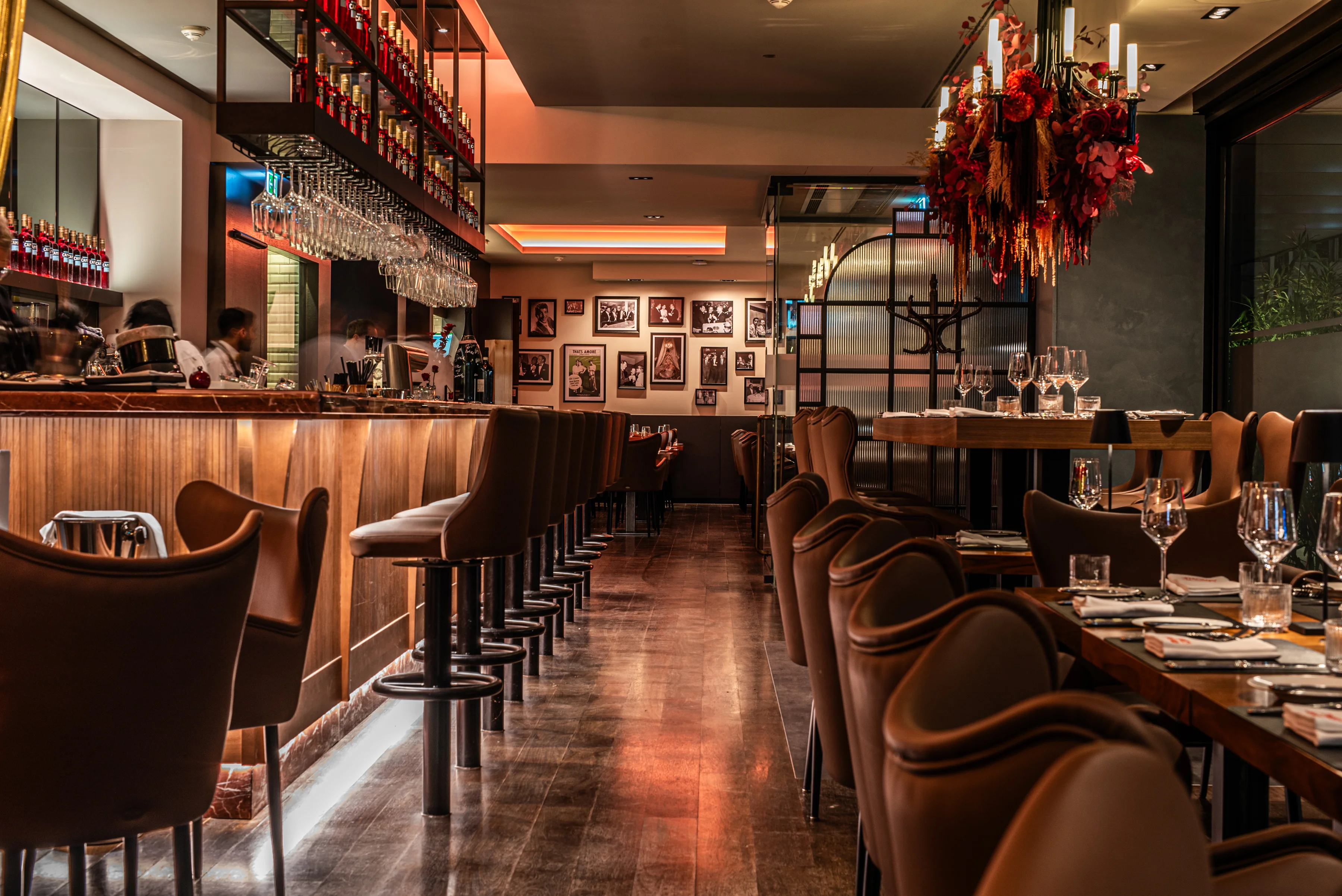 Stilvoll eingerichtetes Restaurant „That’s Amore“ in Stuttgart mit beleuchteter Bar, eleganten Lederstühlen, gedeckten Tischen mit Gläsern und einer warmen, gemütlichen Atmosphäre.