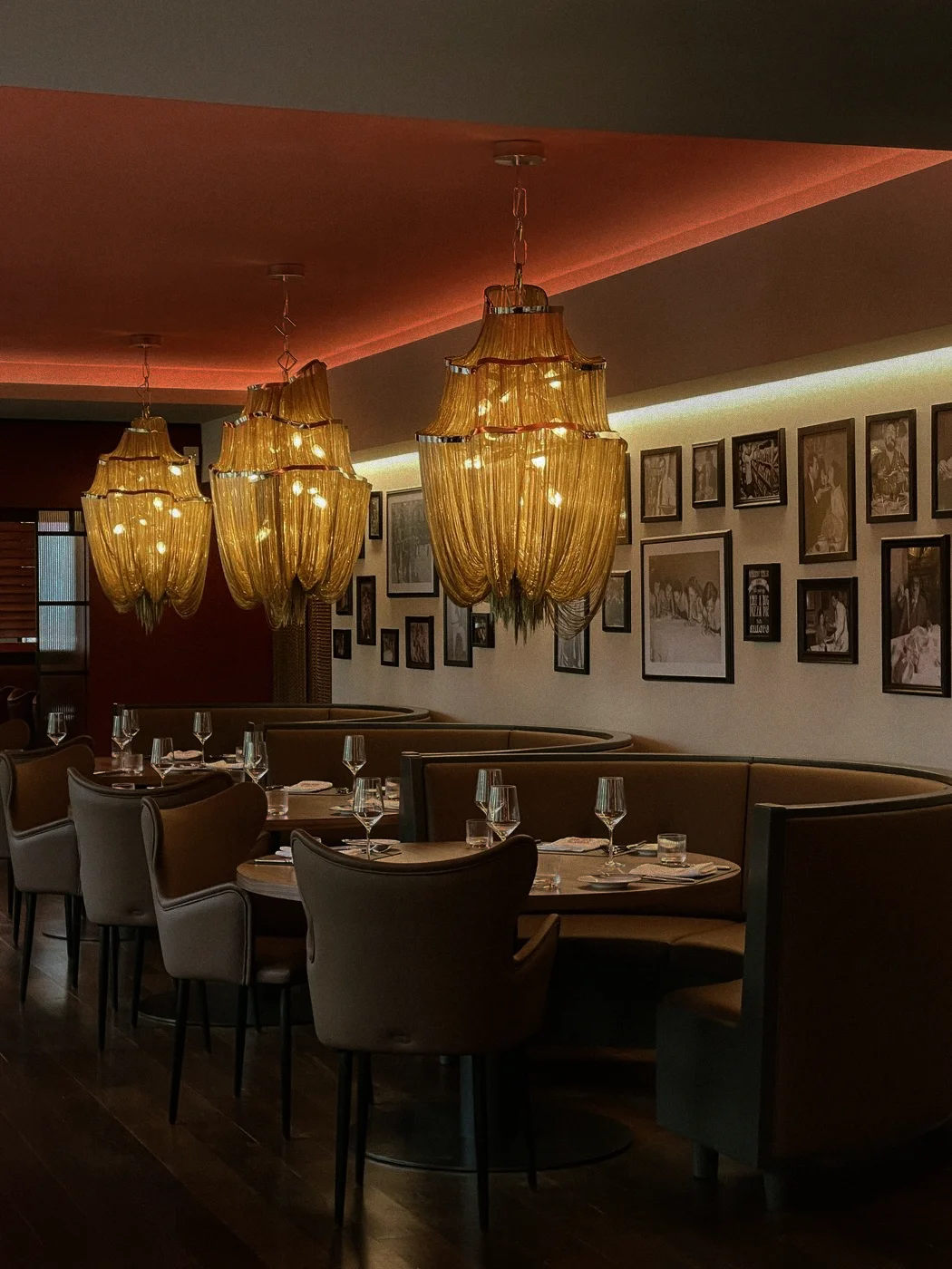 Stilvoll eingerichteter Restaurantbereich mit warmen Licht, Kronleuchtern und Bildern an der Wand.