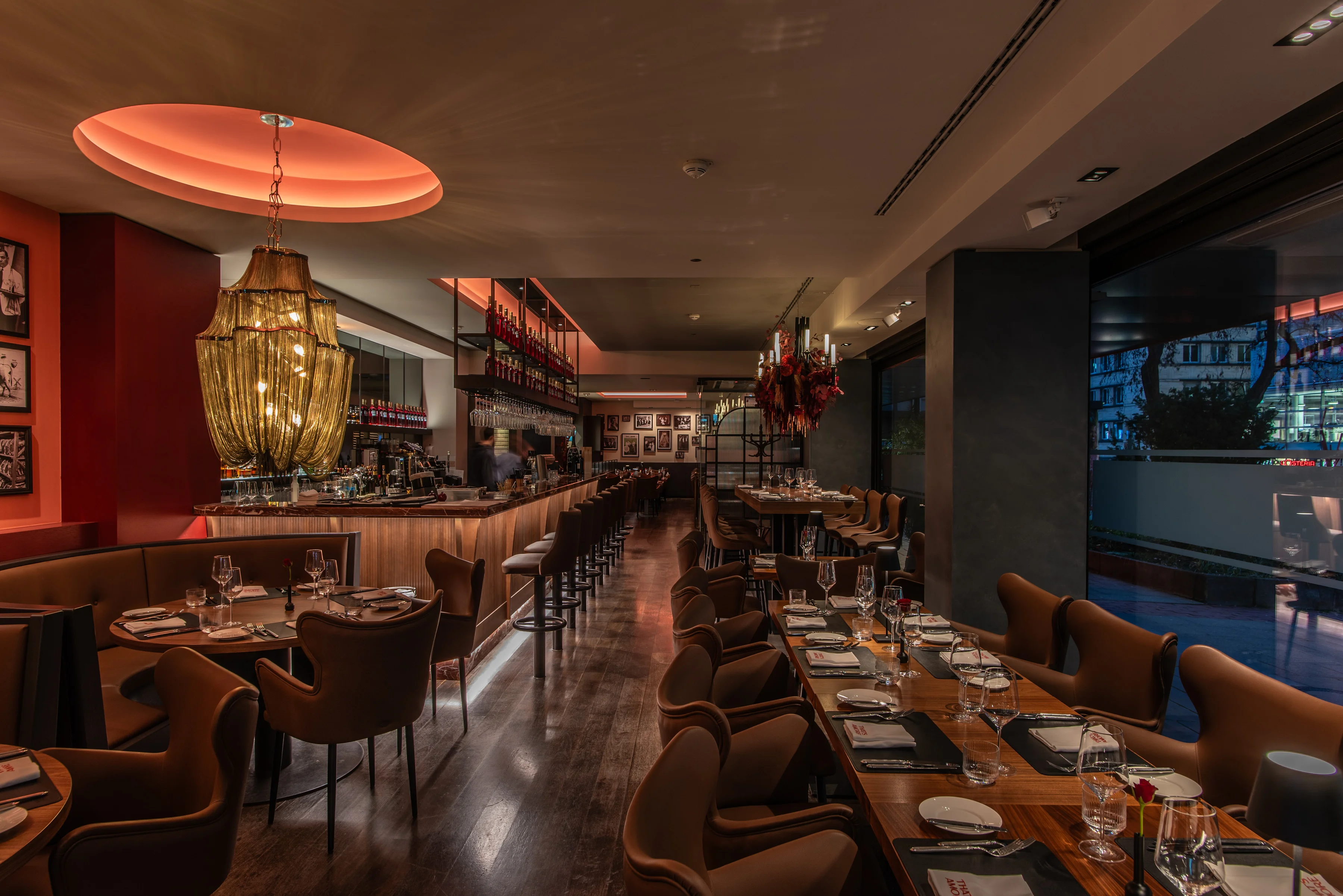Stilvoll eingedeckte Dining Area im Restaurant That’s Amore Stuttgart mit elegantem Kronleuchter, langer Bar und modernem Ambiente in warmem Licht.
