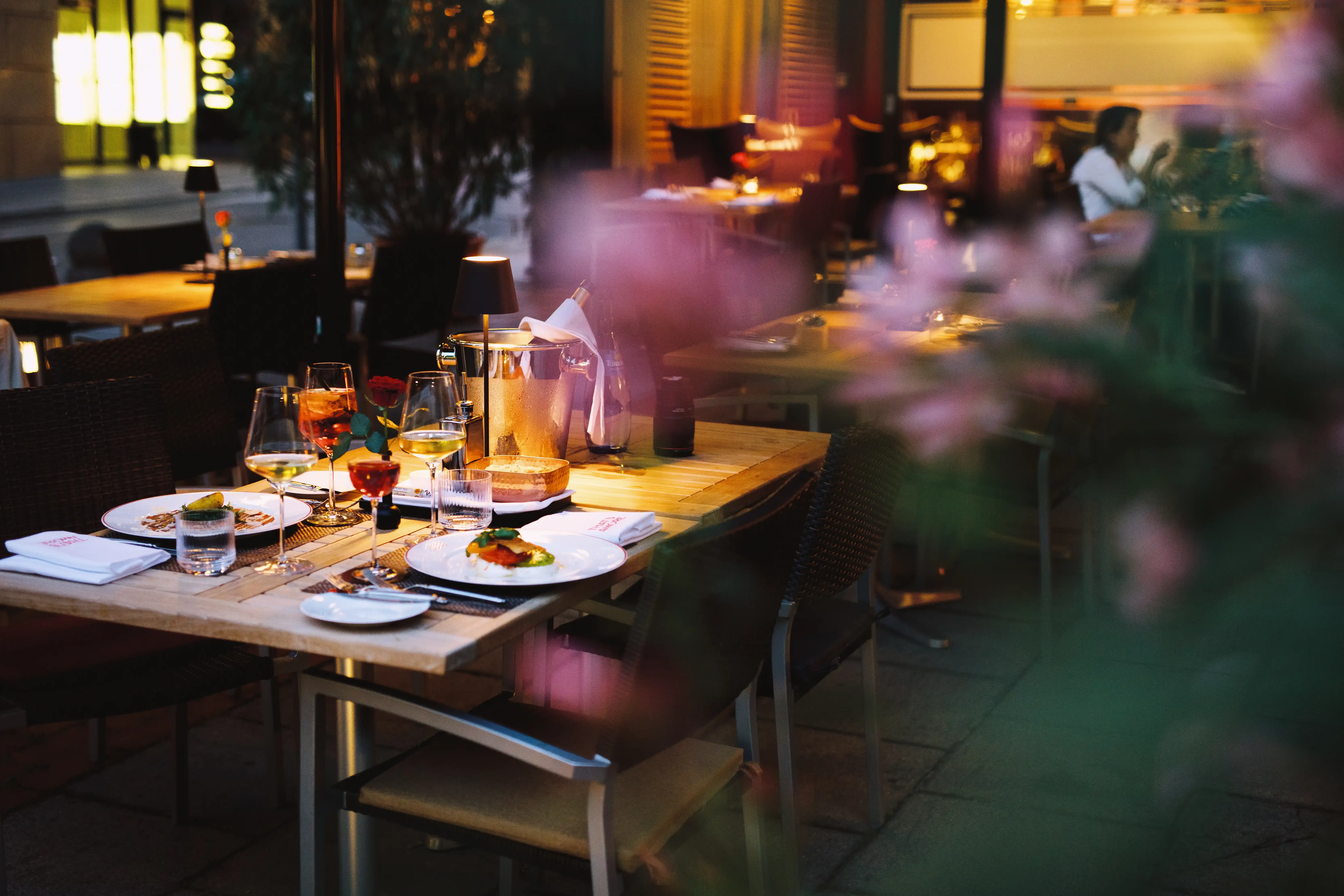 Stimmungsvoll gedeckter Tisch auf der Terrasse des Restaurants That’s Amore in Stuttgart, mit Wein, Vorspeisen und romantischer Beleuchtung im Abendlicht.