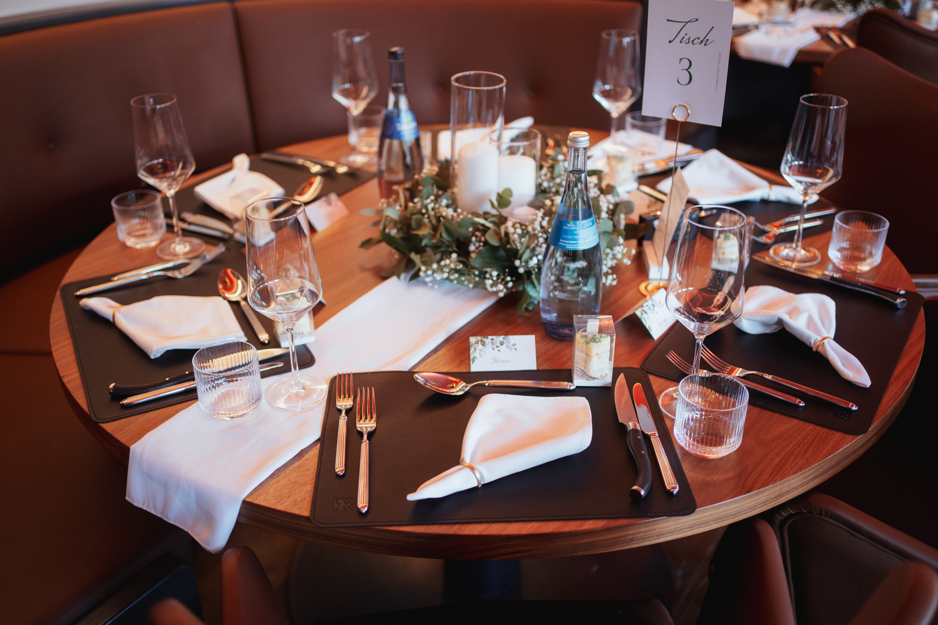 Festlich gedeckter runder Tisch im Restaurant That’s Amore Stuttgart mit eleganter Tischdeko, Kerzen und Namenskarten.