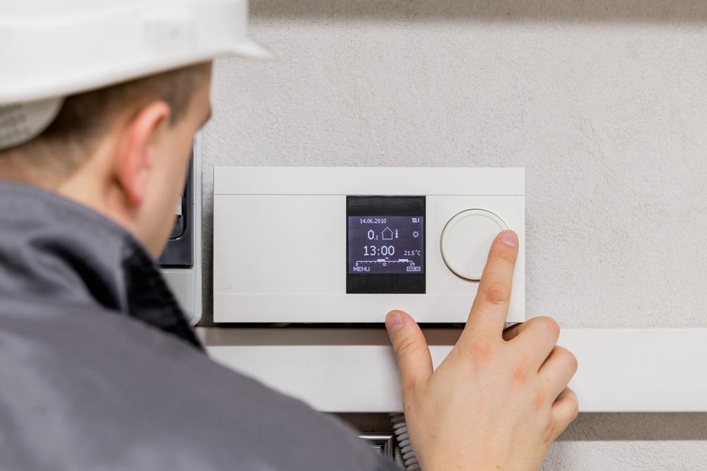 Technician checks a thermostat settings.