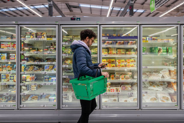 The image depicts a person shopping in the frozen or refrigerated food section of a grocery store or supermarket.