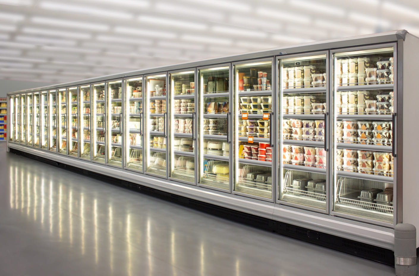 A row of commercial refrigerators in a supermarket. All refrigerators are stocked with food items.
