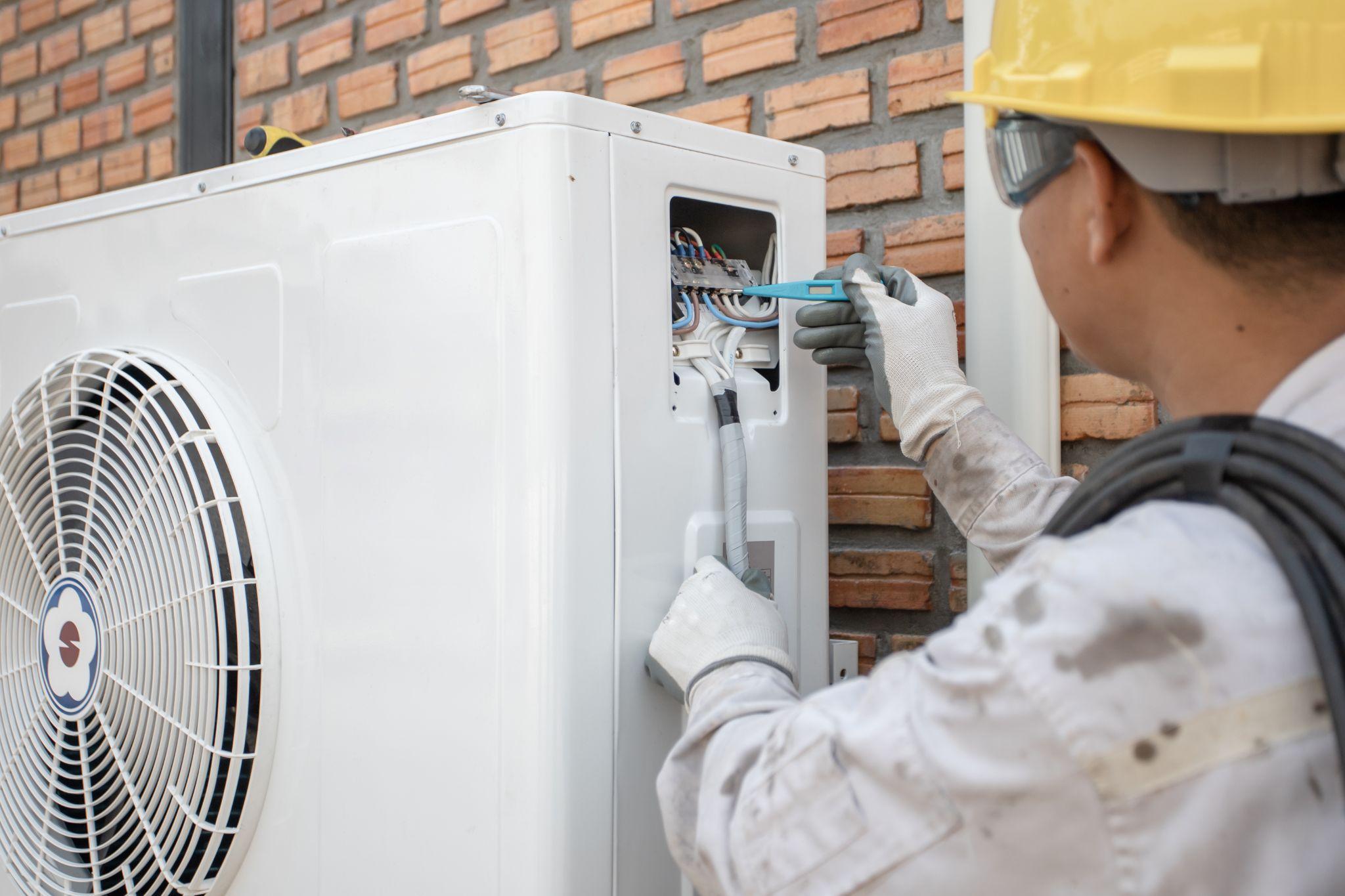 Technician performing electrical test on an outside heat pump