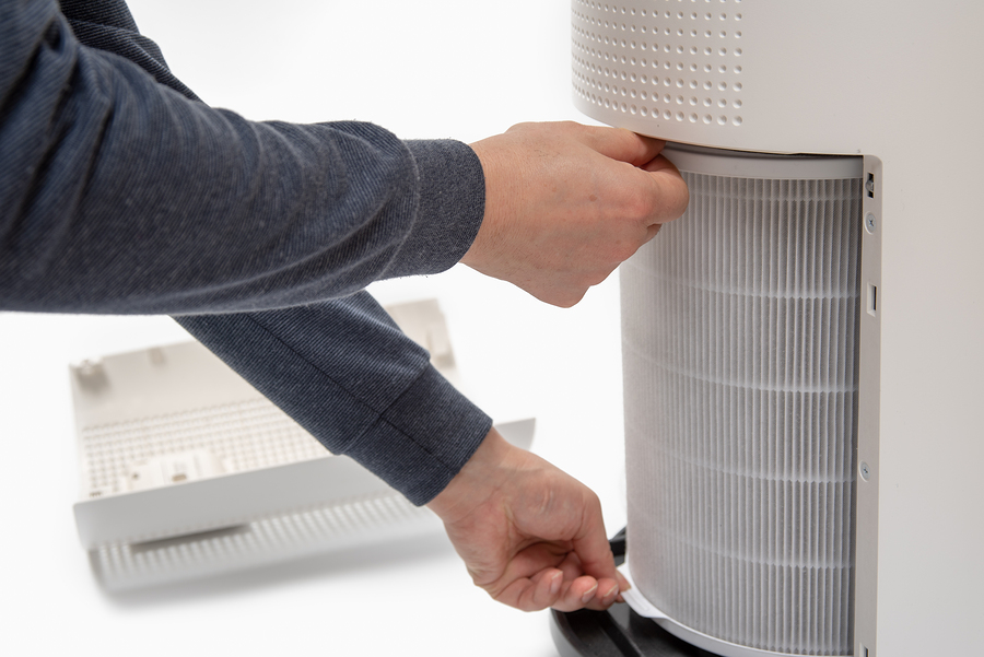 The image shows someone handling a filter from an air purifier, likely in the process of replacing or cleaning it.