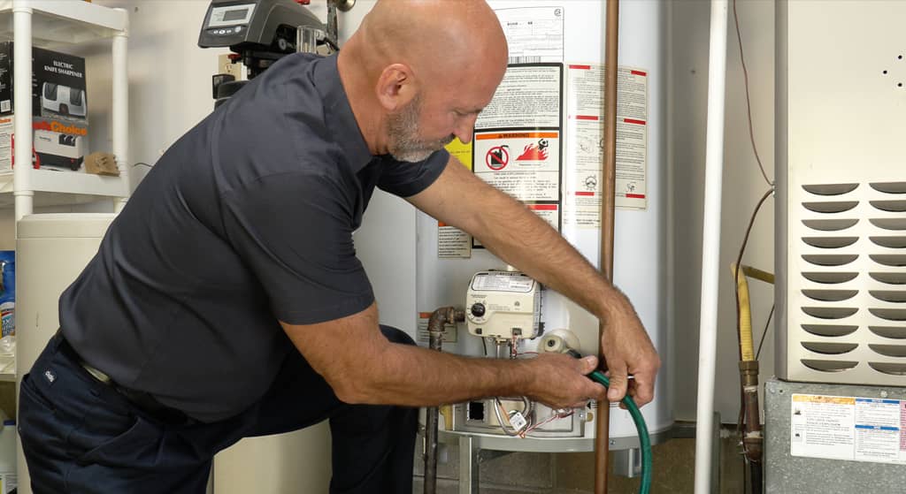 This image depicts a technician performing maintenance or repair on a water heater.