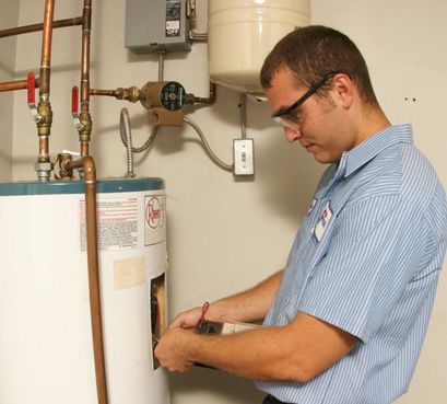 A technician in a blue pinstripe shirt works on a water heater.