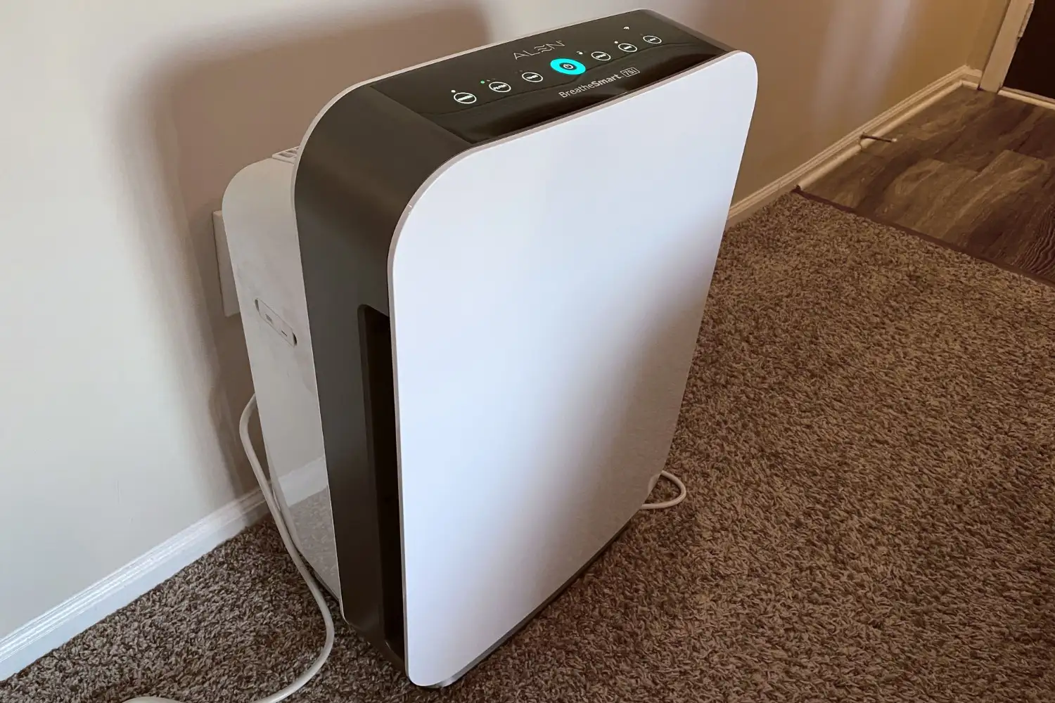 Modern white air purifier standing on carpet.