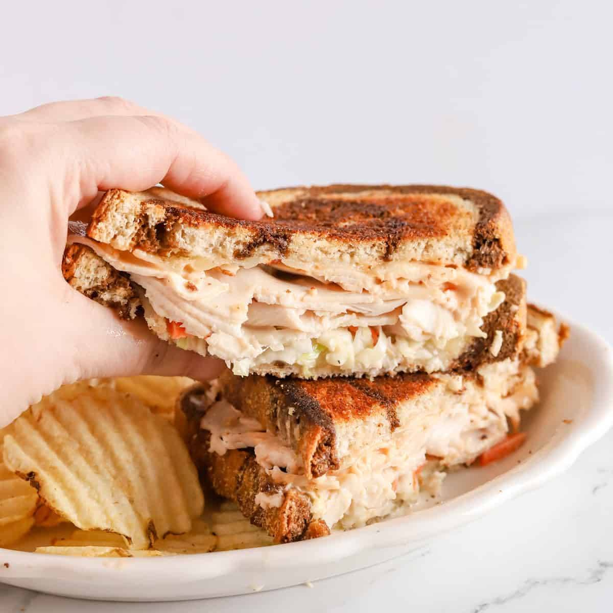 A Turkey Rachel sandwich on toasted rye with chips