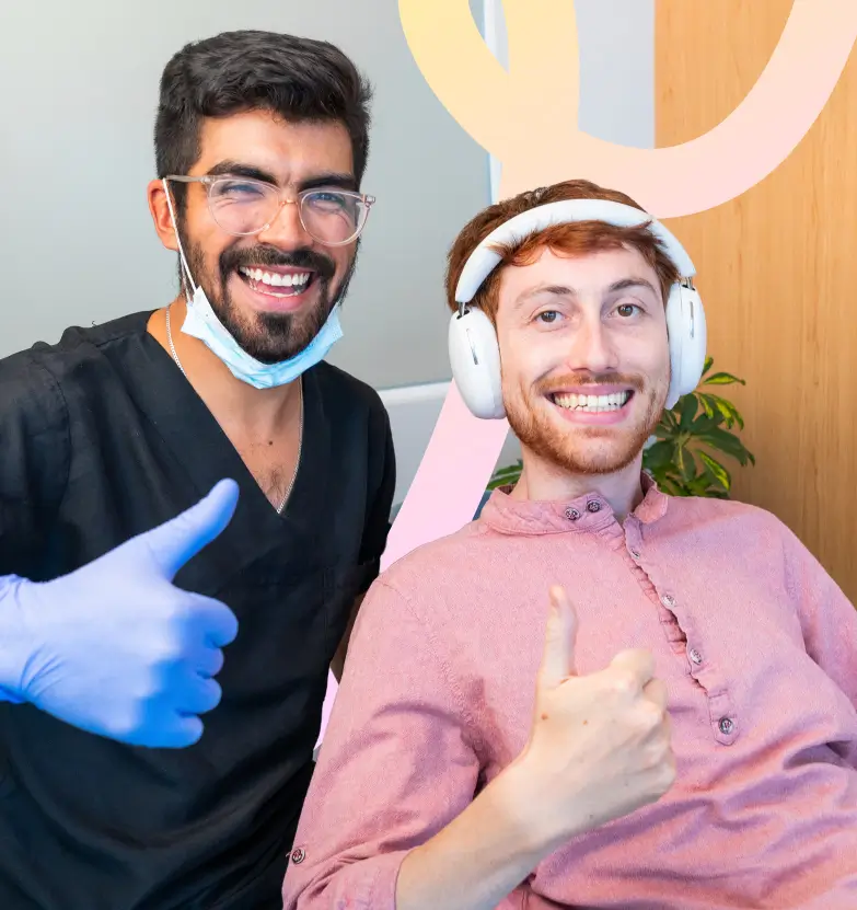 Dentista sonriente levantando pulgar junto a paciente satisfecho
