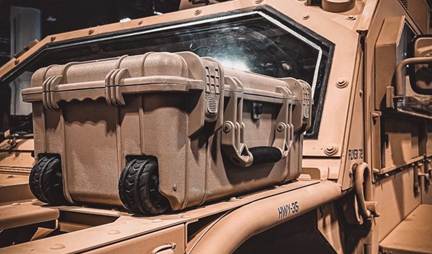 Rugged tan storage case with wheels mounted on armored military vehicle