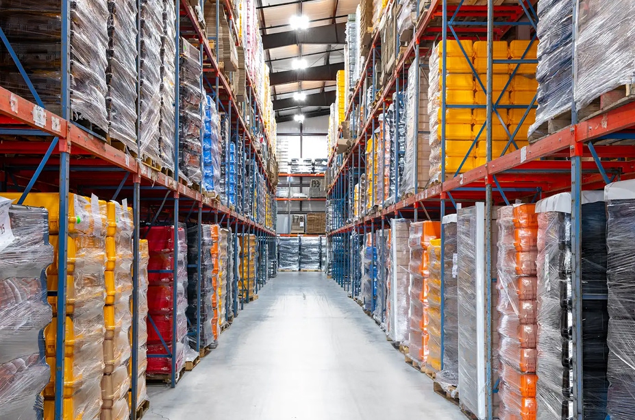 Well-organized warehouse aisle with stacked pallets and shelving.