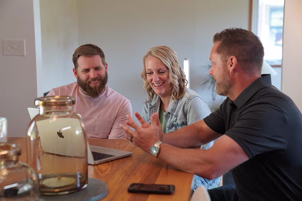 company representative sitting with customers at kitchen table smiling during a presentation