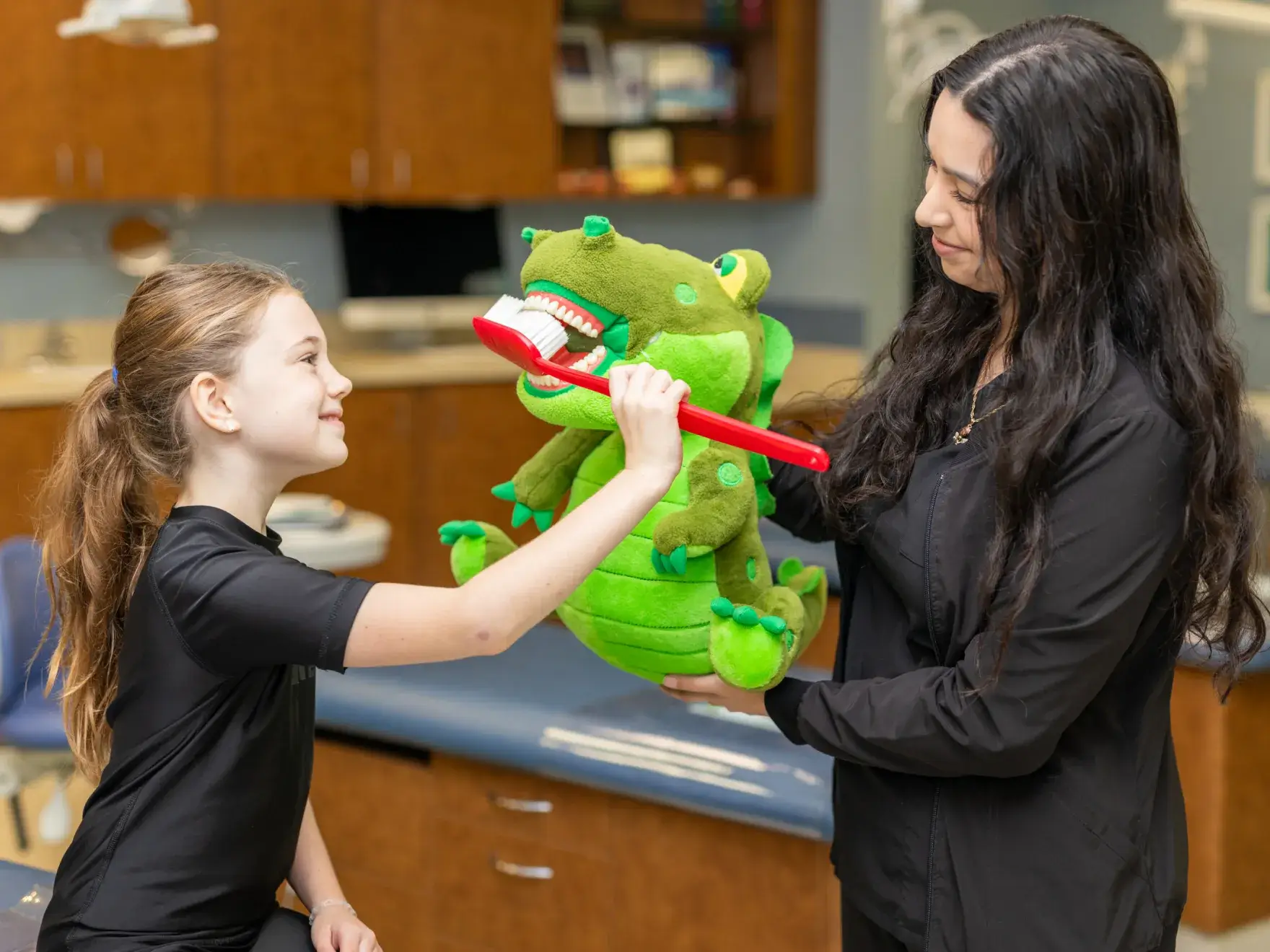 A woman holding a stuffed frog and a toothbrush.
