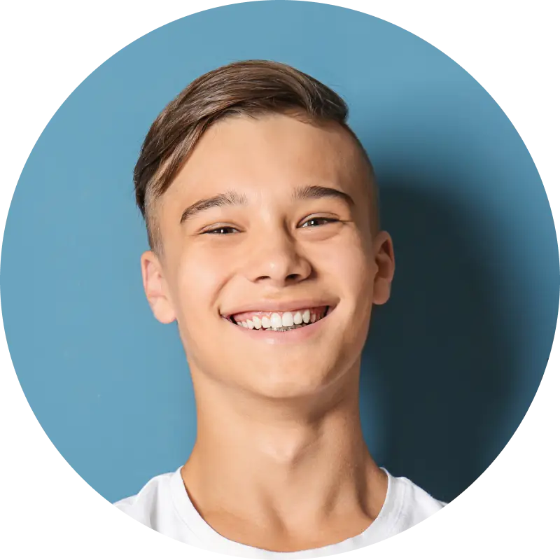 Smiling teenage boy with short brown hair against a blue background.