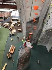 A climber transitions from the stalagmite up onto the stalactite feature.