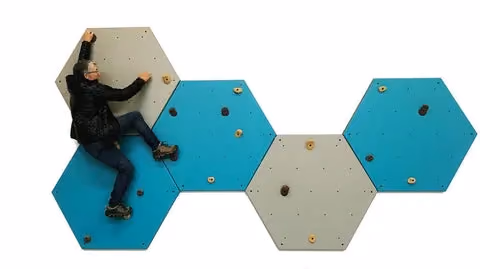 woman climbs on a gray and blue wall of hexes