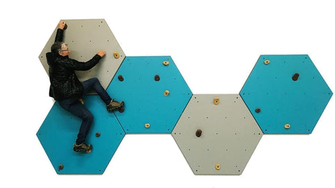 woman climbs on a gray and blue wall of hexes