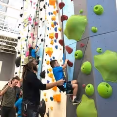 Jason Momoa, star of Aquaman, helps a boy climb the Eldorado Climbing Walls wall at the Variety Boys and Girls Club in Los Angeles.