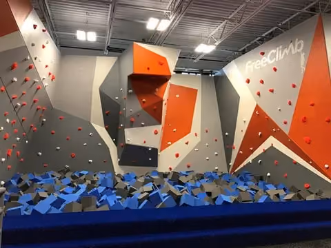A foam pit sits below the bouldering wall in the FreeClimb area of the Asheville Sky Zone