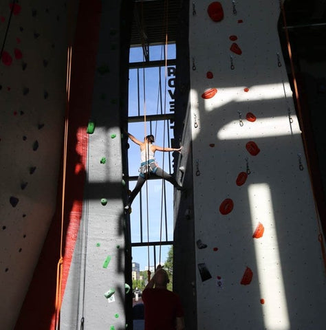Woman straddles the chimney at an indoor rock climbing gym