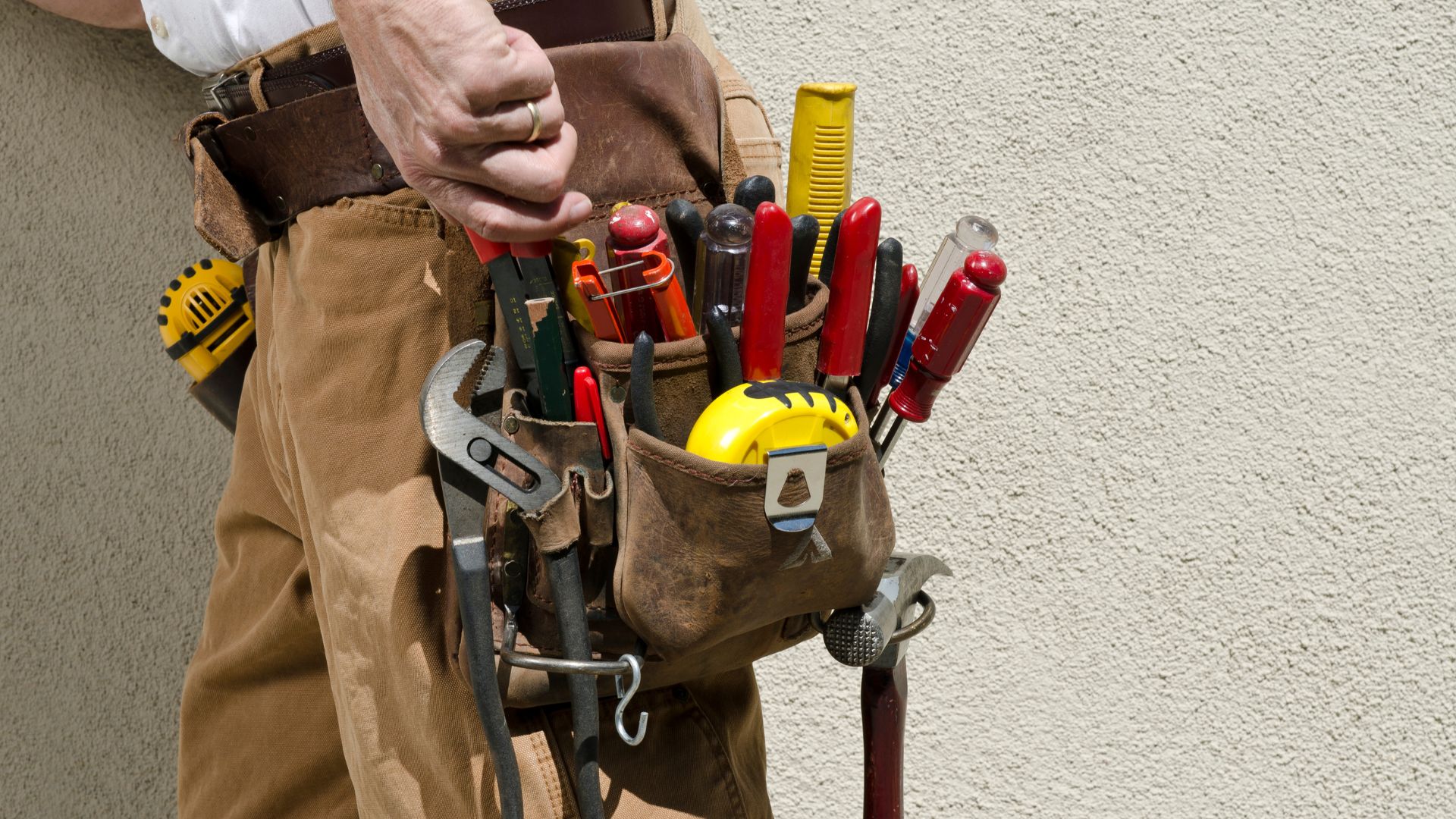 A man holding a tool belt full of tools
