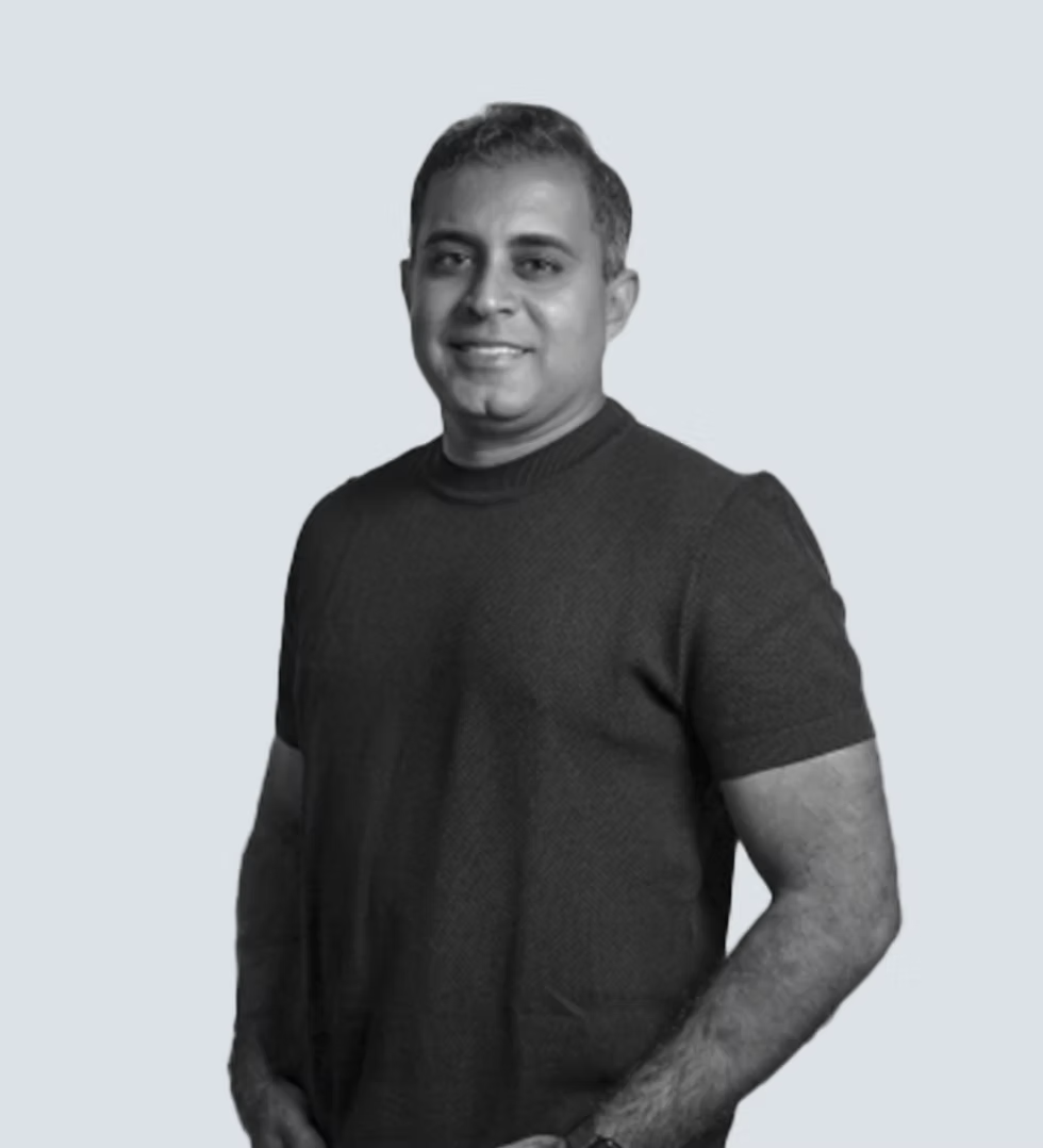 Portrait of a smiling man wearing a short-sleeve knit shirt against a light background.