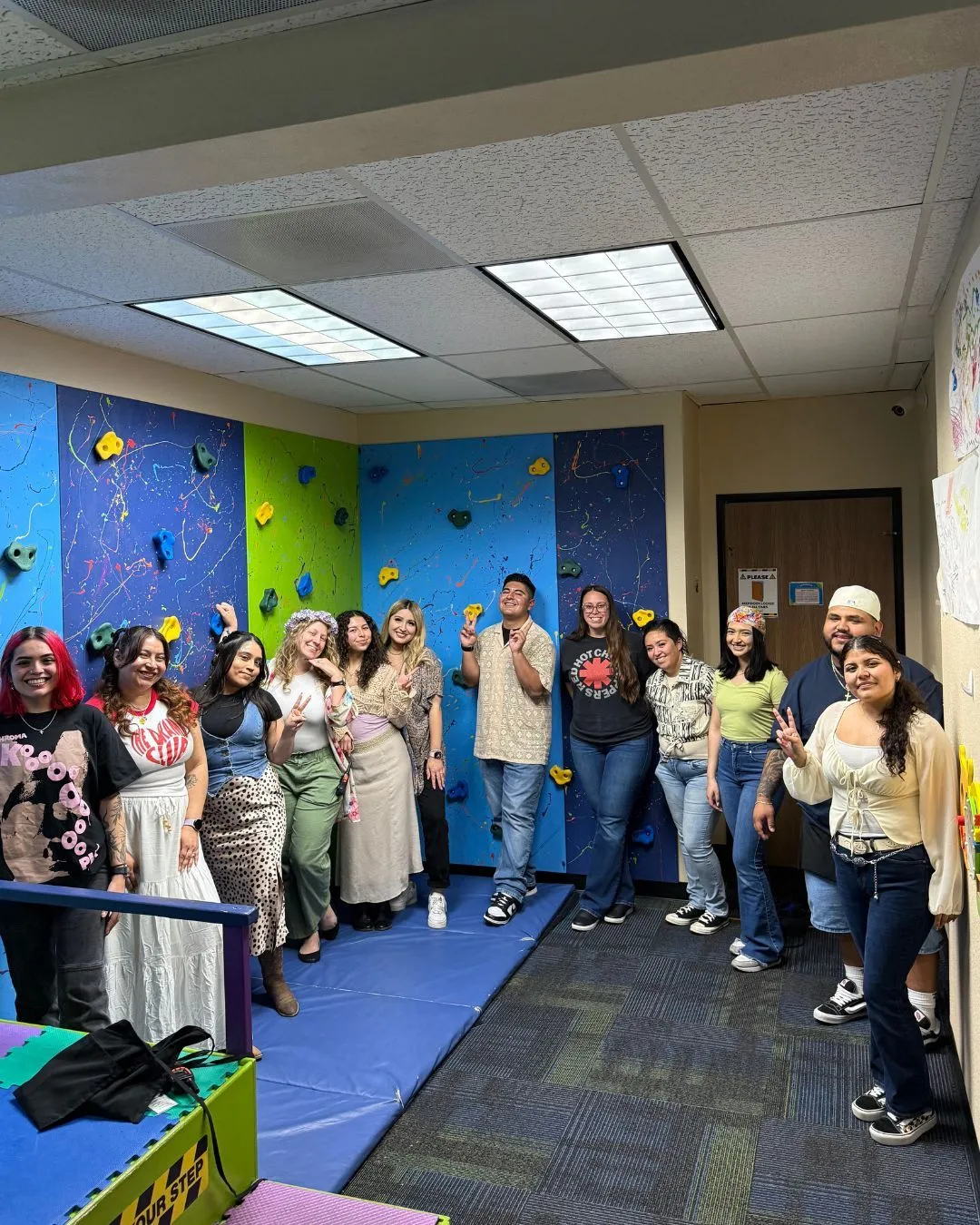 Team group photo in front of a play gym with blue and green climbing walls.