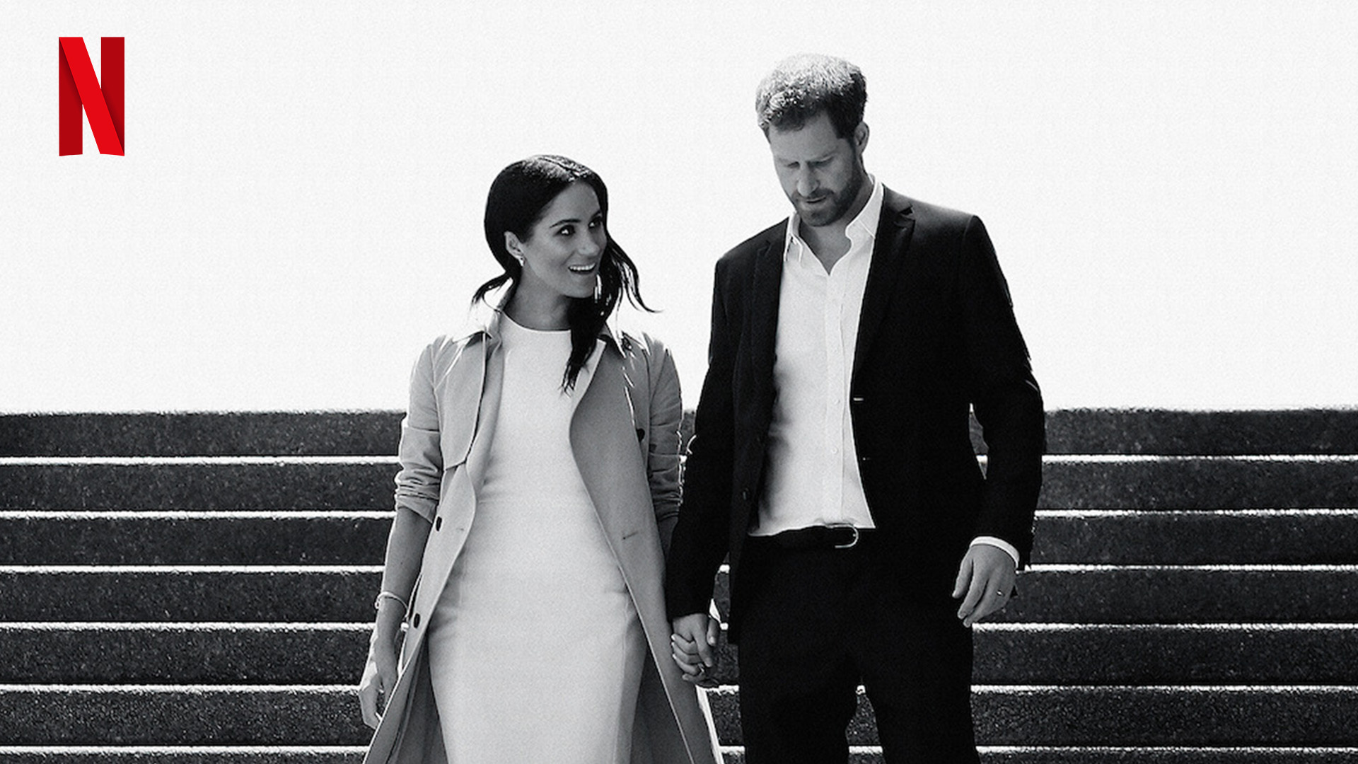 Harry and Meghan holding hands and walking down stairs, with Netflix logo on the top left corner
