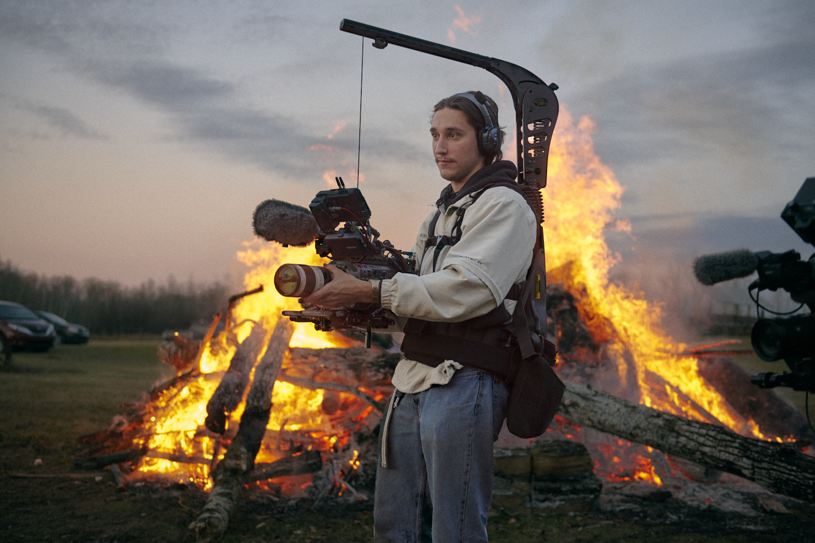 Lucas Cabaj Guerra Pictured operating a camera in front of a large bonfire operating a documentary camera.