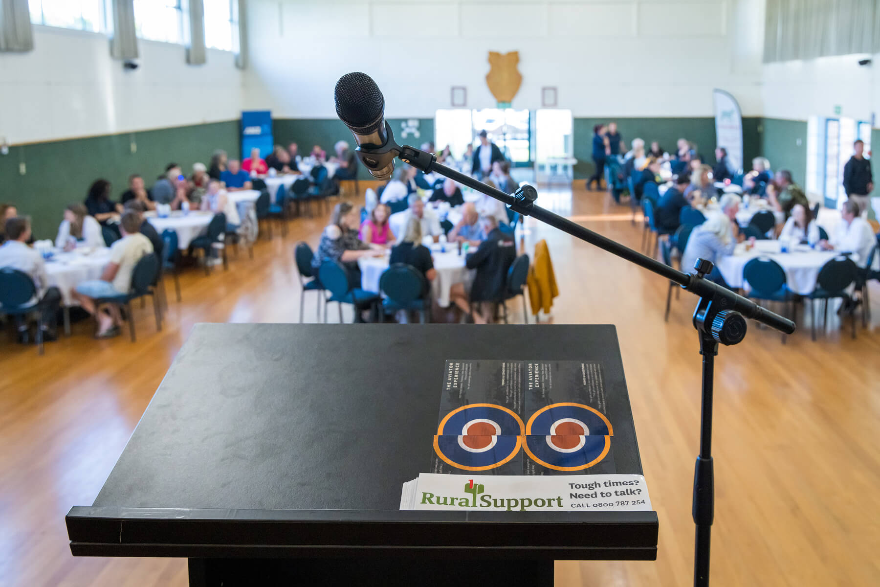 A speakers podium with groups of people seated at tables in the background.