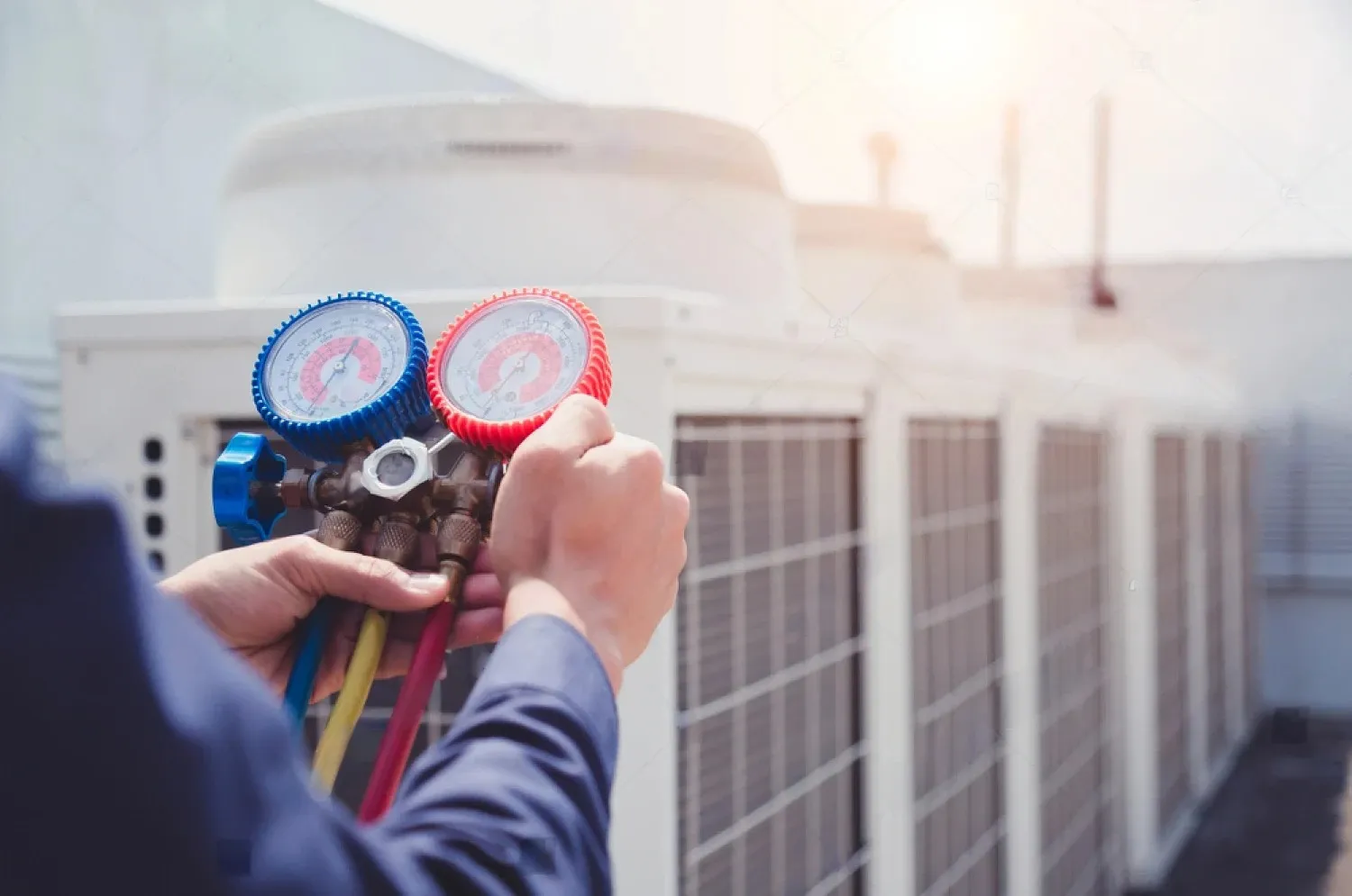 Technician checking pressure gauges on air conditioning unit exterior