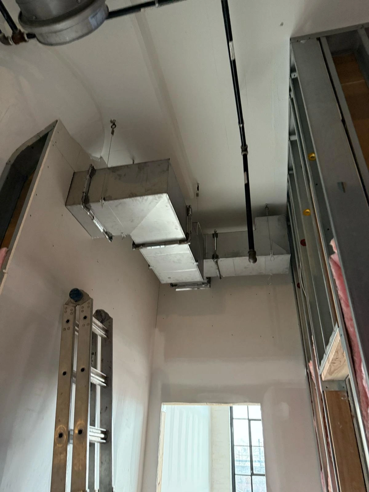 Exposed HVAC duct and return air vent installation in a white-walled room
