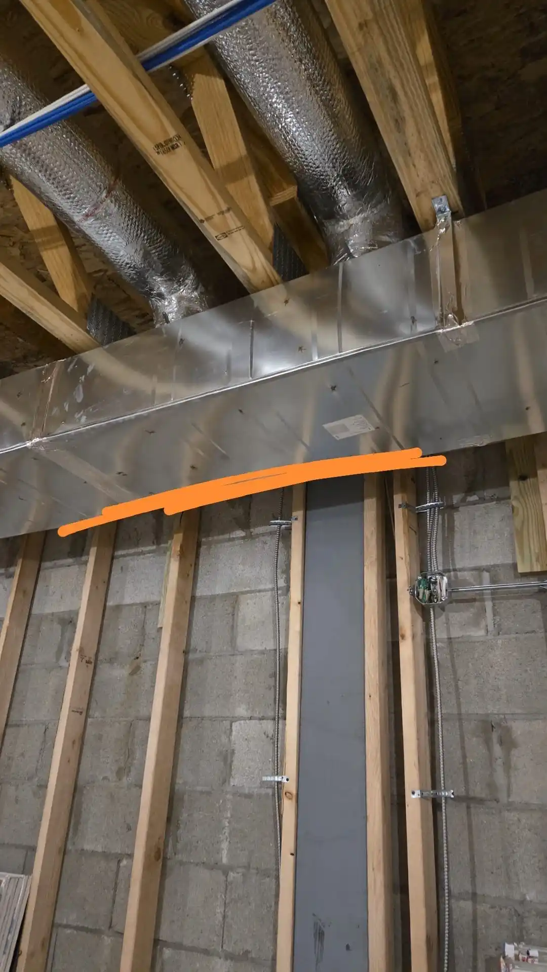 HVAC duct installation in progress inside residential wall framing with insulated flexible ducts