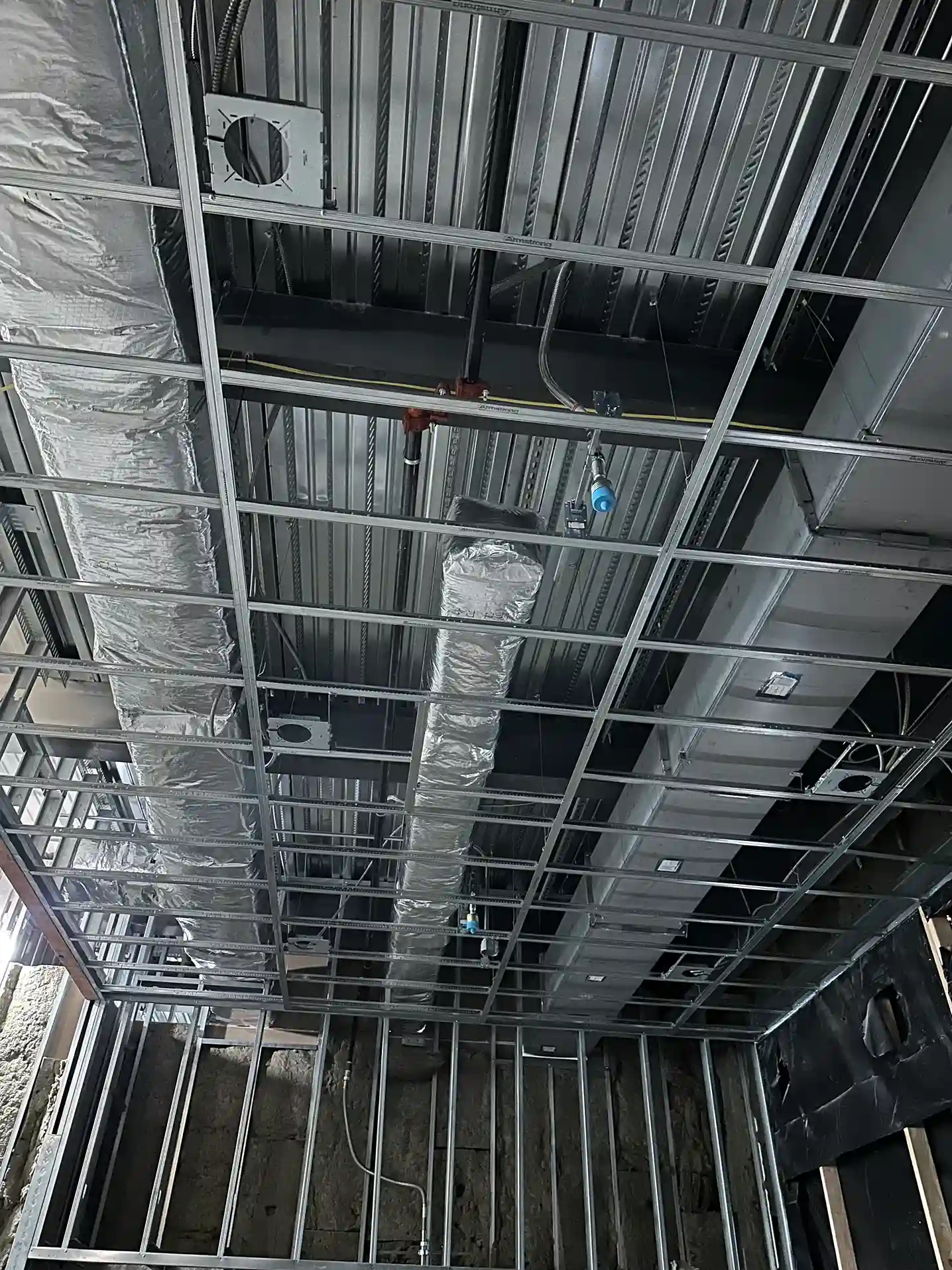 Exposed ductwork and piping installation during commercial HVAC construction