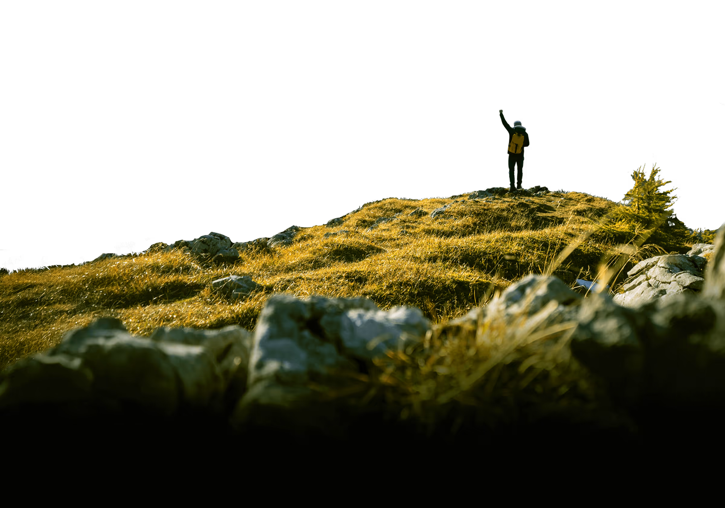Hiker standing on rocky grass hilltop in silhouette against black sky.