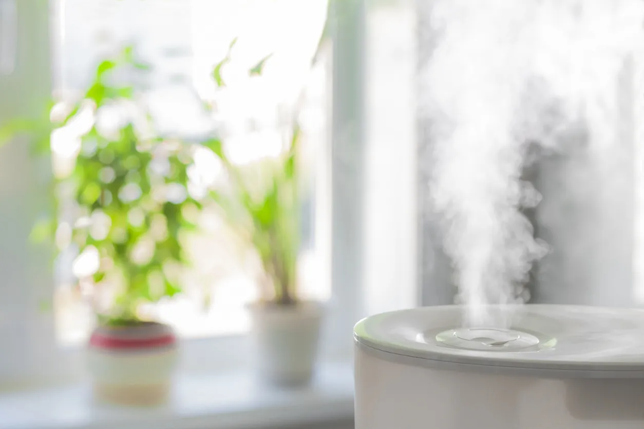 A close-up of a humidifier releasing mist in a bedroom