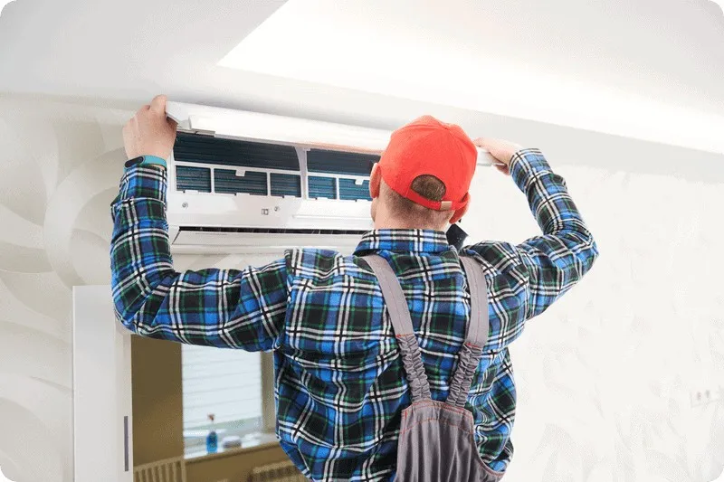 Technician reaching up to service unit.