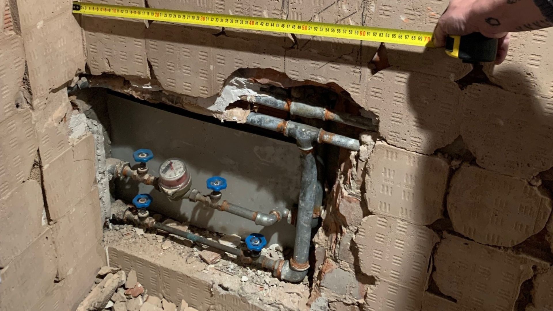 Profesional de Carmona & Crespo tomando medidas durante reforma de baño con tuberías a la vista