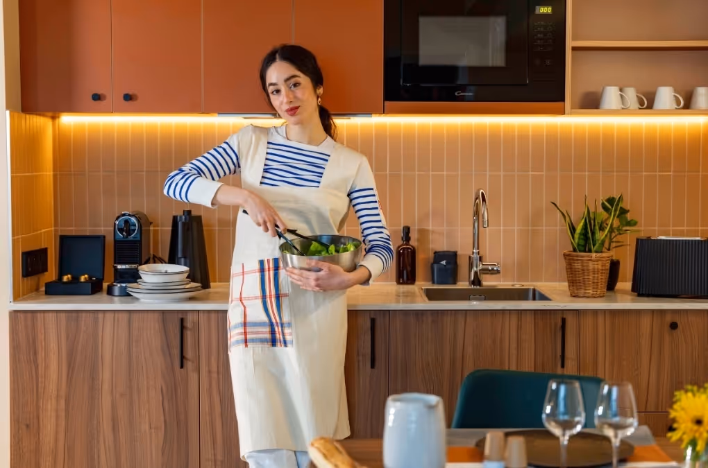 Femme qui cuisine dans un appartement meublé Yuna Montmartre, résidence hôtelière idéale pour séjour affaires ou bail mobilité.