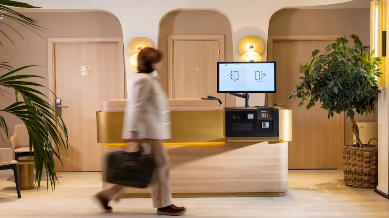Person walking past the reception desk in a hotel residence for business stays and long-term rentals, Yuna.