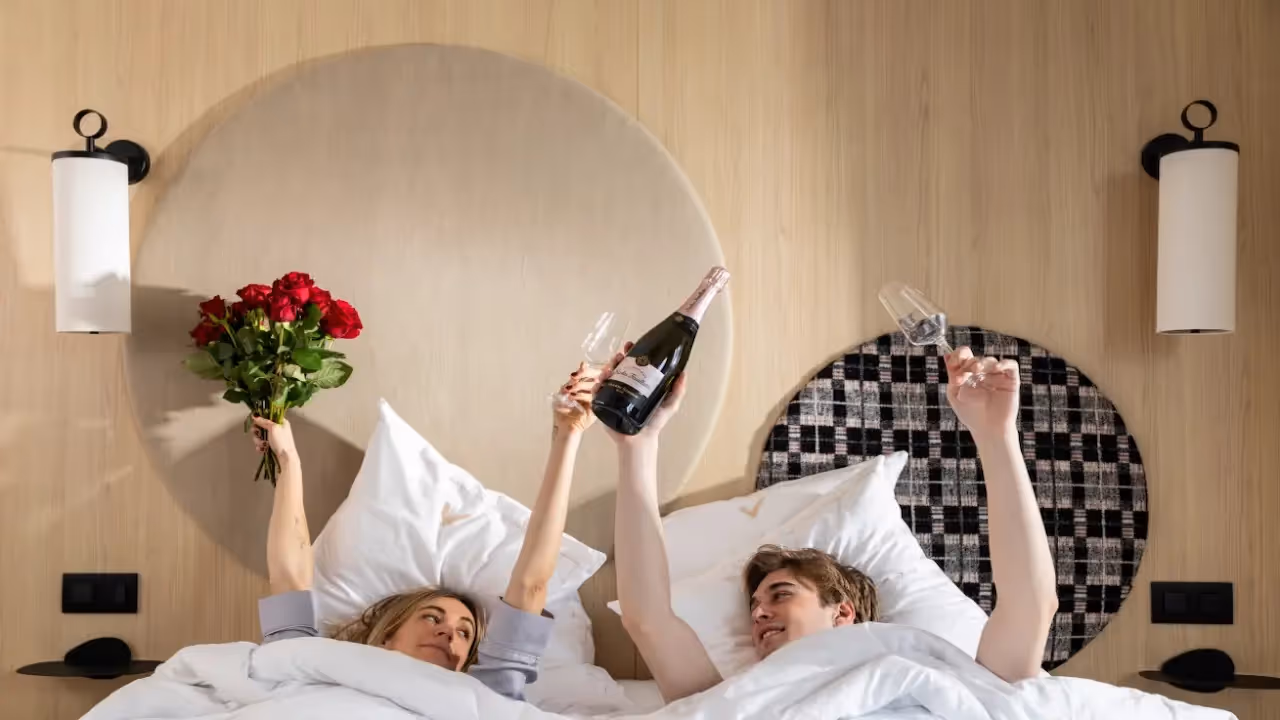 Couple in a bed with champagne and a bouquet of flowers in an apartment hotel furnished for a romantic stay, Yuna.