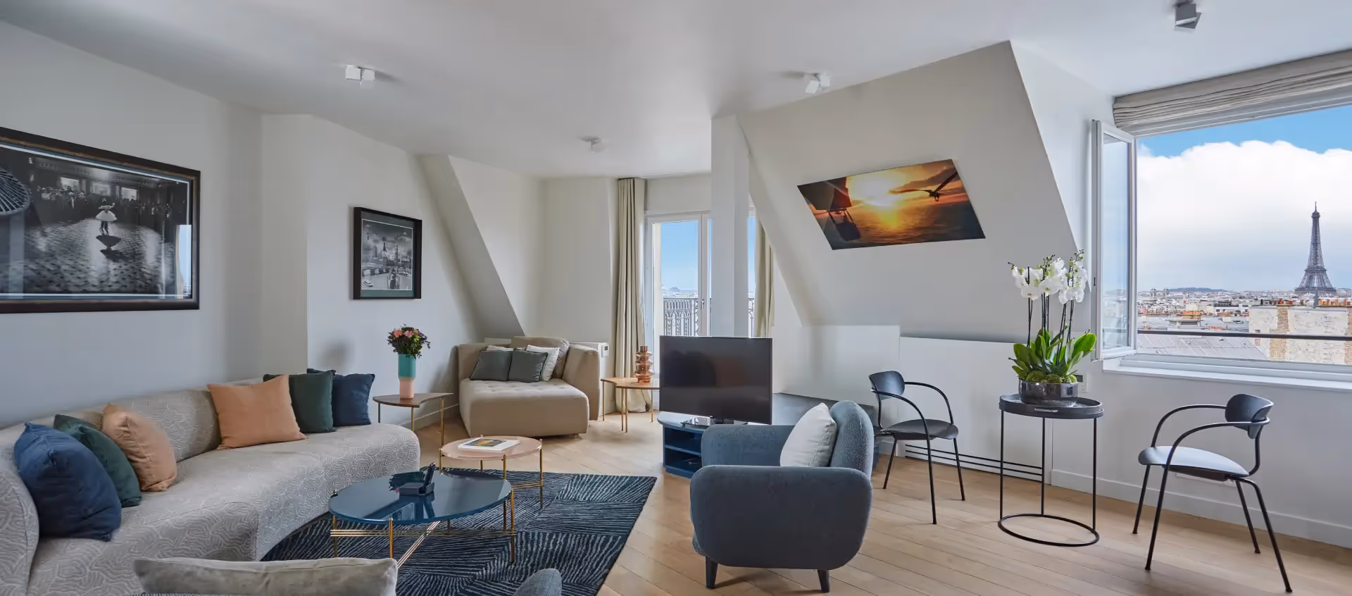 Living room decorated with paintings on the walls and a view of the Eiffel Tower in a furnished apartment for business stays and mobility leases, Yuna.