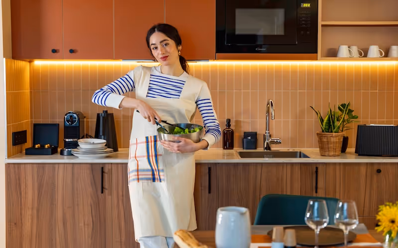 	Femme cuisinant dans la kitchenette moderne de l’appart hôtel Yuna Montmartre.
