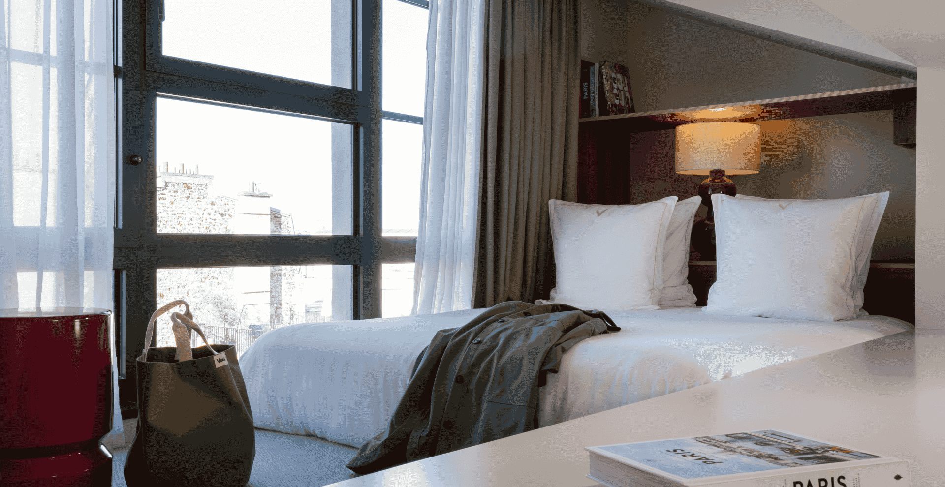 Chambre lumineuse avec lit double, grandes fenêtres et décoration élégante dans un hôtel à Paris