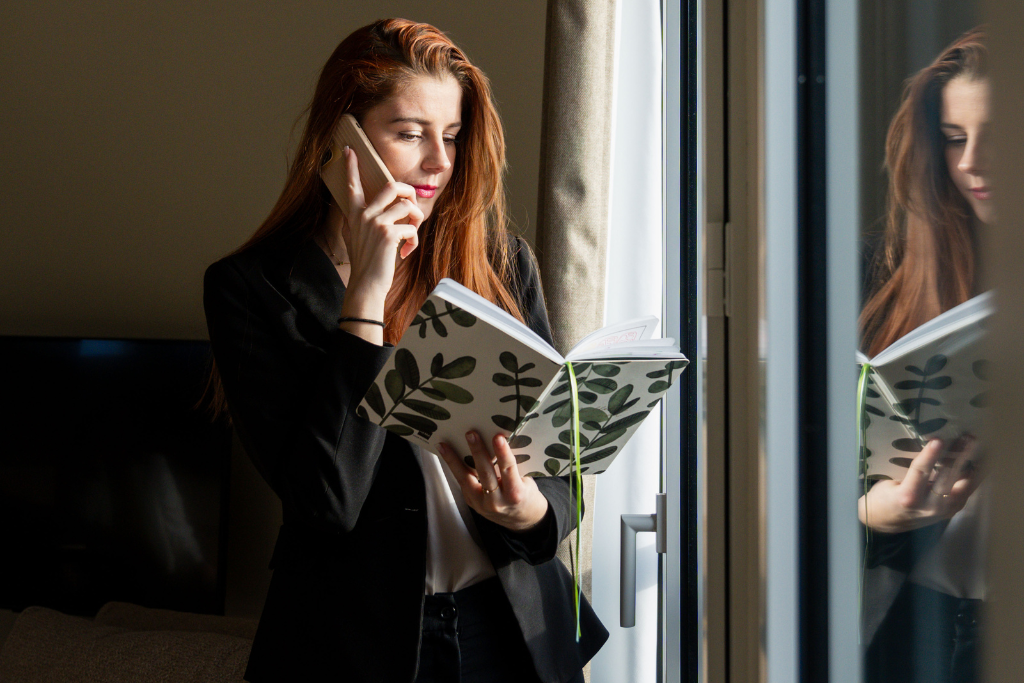 Femme d'affaires en déplacement lisant un ouvrage tout en échangeant au téléphone